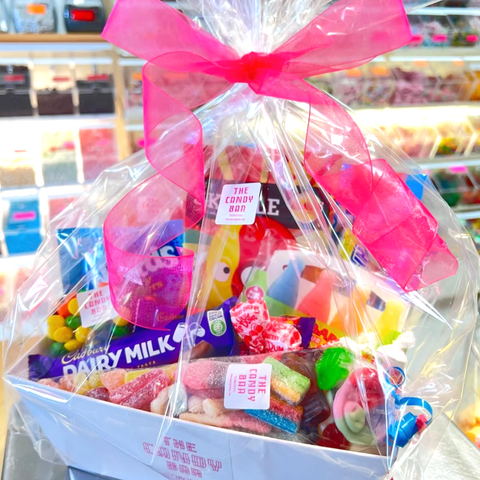 Gourmet candy basket with a pink bow in a store setting
