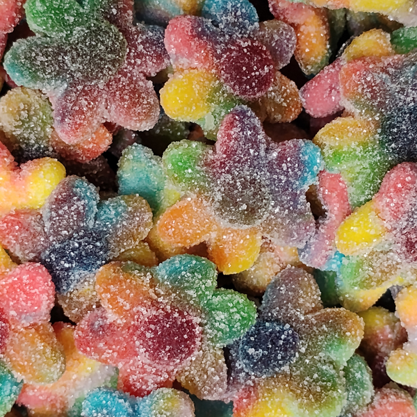 A close-up pile of rainbow-colored sugar-coated gummy candies, showing multicolor shapes with a white sugar dusting.
