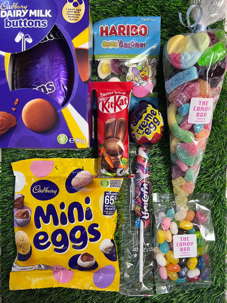 Assorted Easter candy including Cadbury Mini Eggs, Haribo, KitKat, and a candy cone on grass. Bunny Box assortment from The Candy Bar.